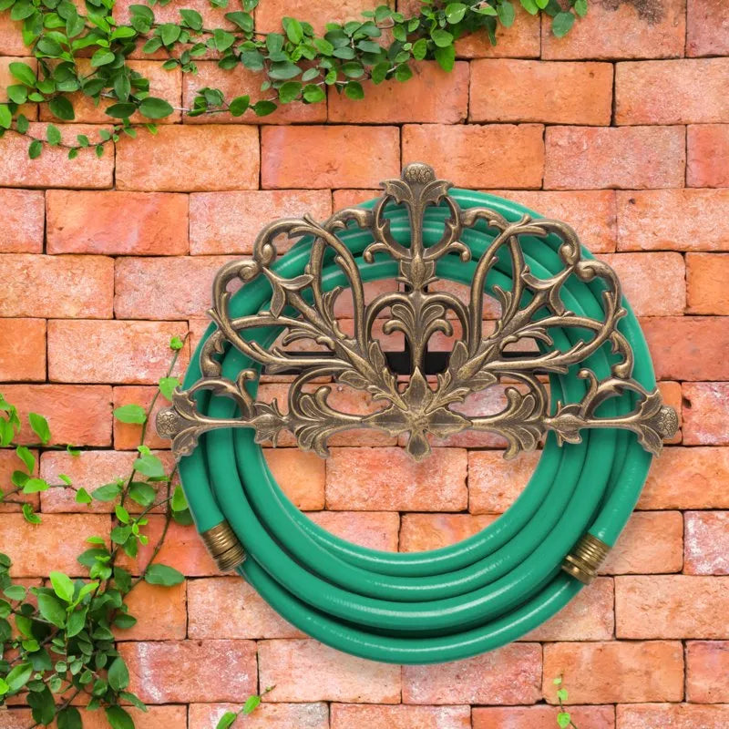 Whitehall Filigree hose holder on a warm brick wall with ivy and green garden hose